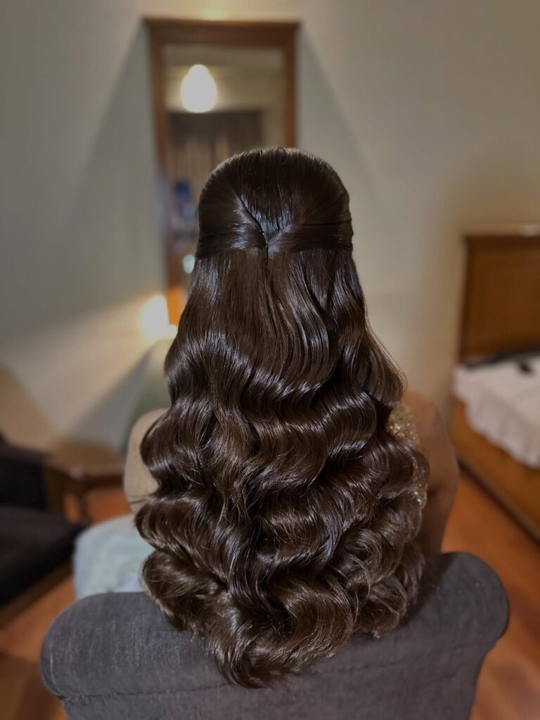 A woman with long curly hair featuring a mahogany to bright copper ombre transition styled in a voluminous high ponytail.
