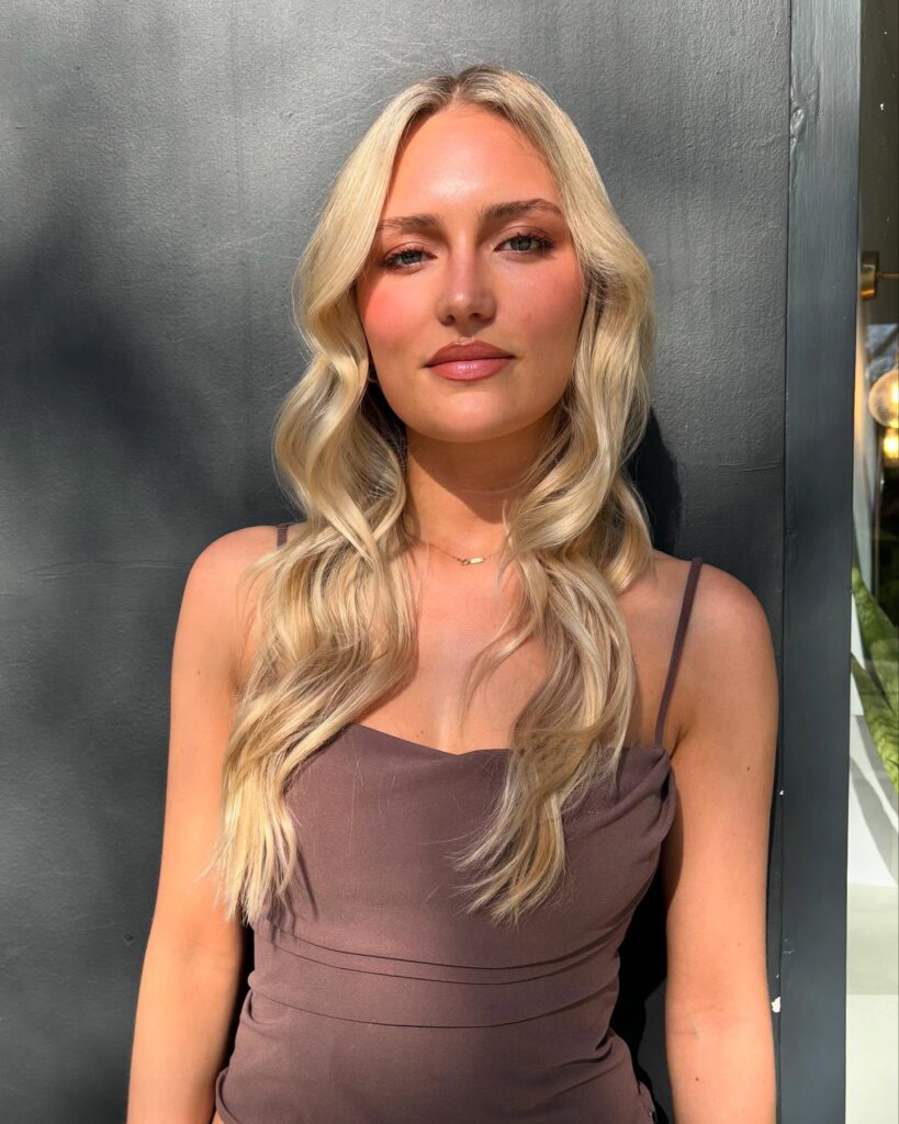 A woman with ash blonde hair in a sleek low chignon decorated with a scattering of small sparkling crystals and a rhinestone hairpiece.