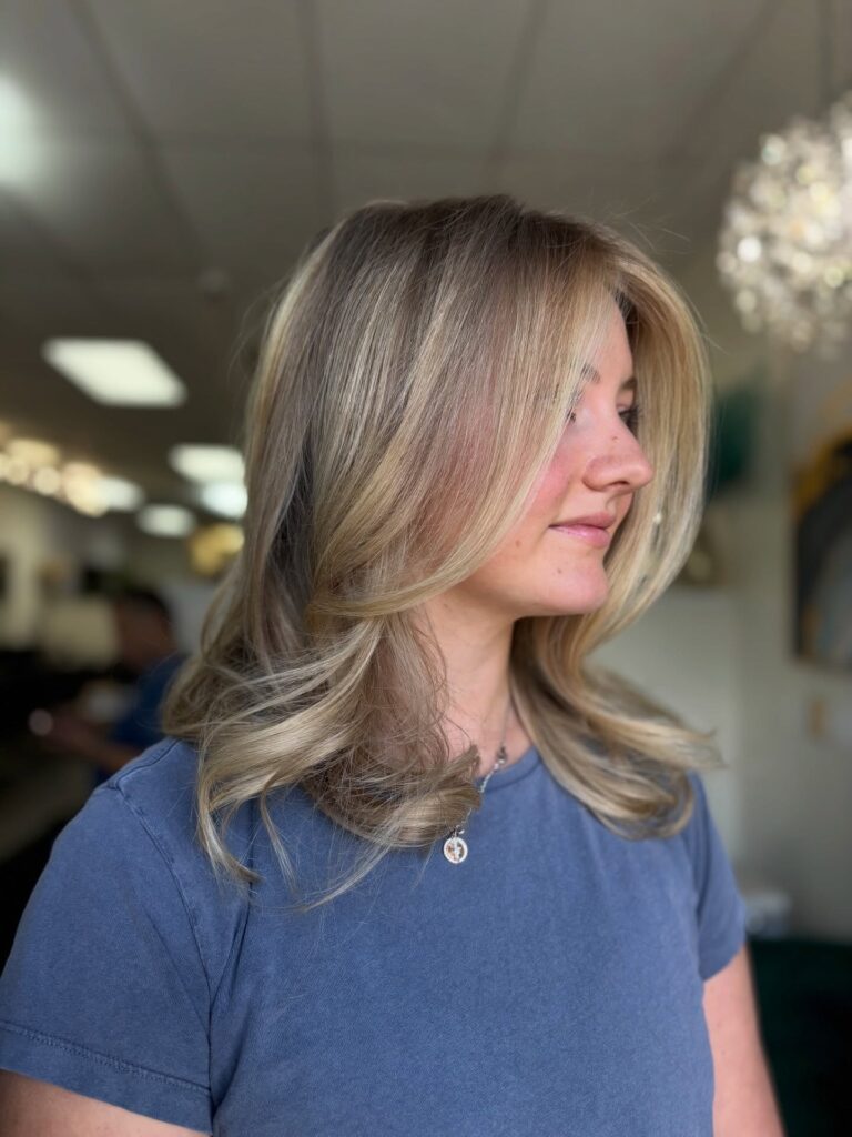 A woman with a shoulder length beige blonde lob featuring soft inward curved layers and a side part.