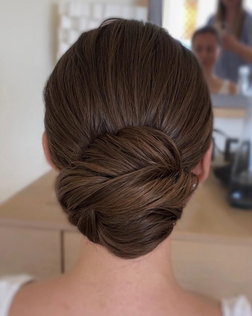 Long hair brushed back into a clean low bun with neatly tucked ends.
