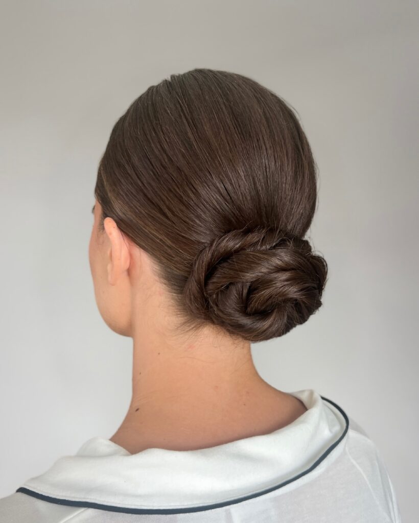 Dark hair styled into a minimal sleek low bun with a sharp clean finish.
