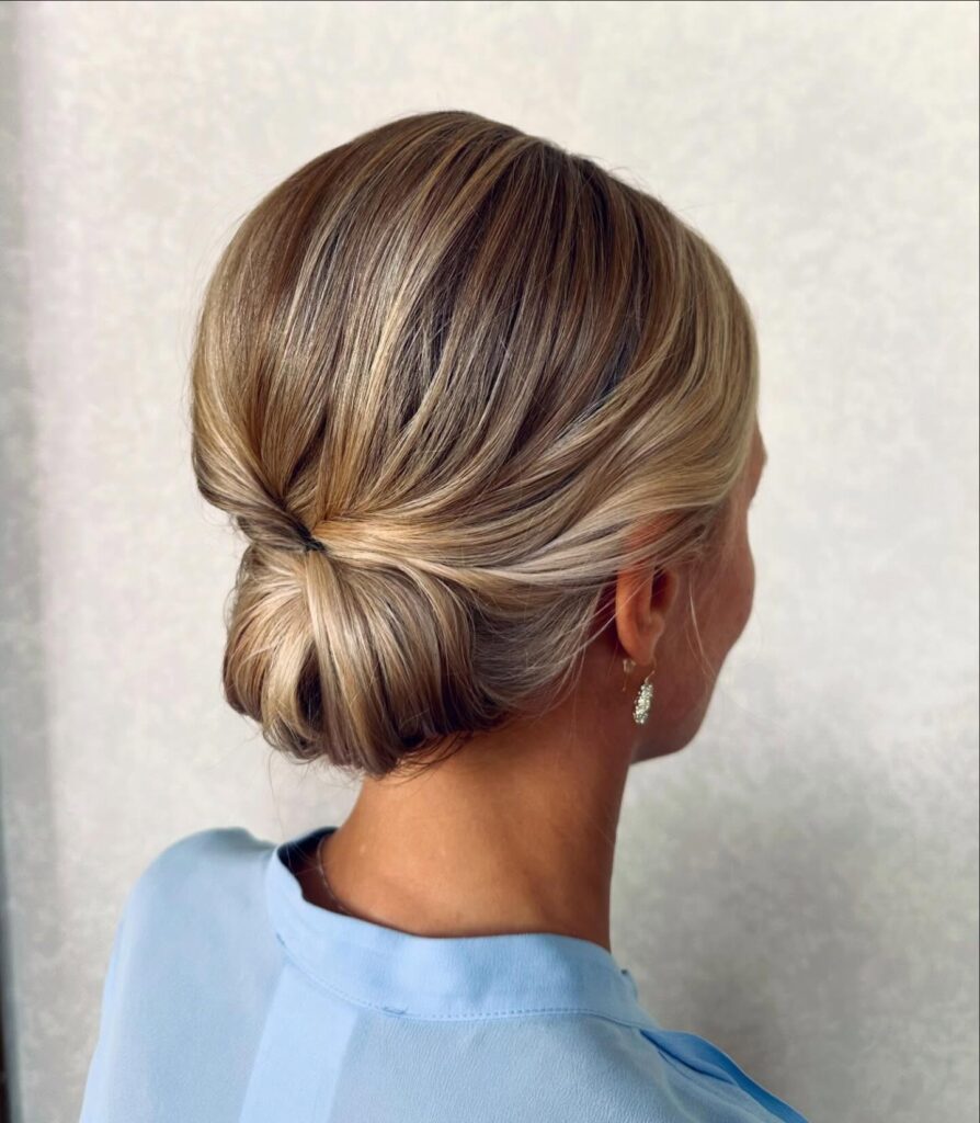 Blonde highlighted hair styled into a twisted low bun with a smooth finish.