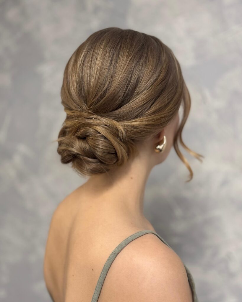 Light brown hair styled into a loose low bun with soft face framing strands.