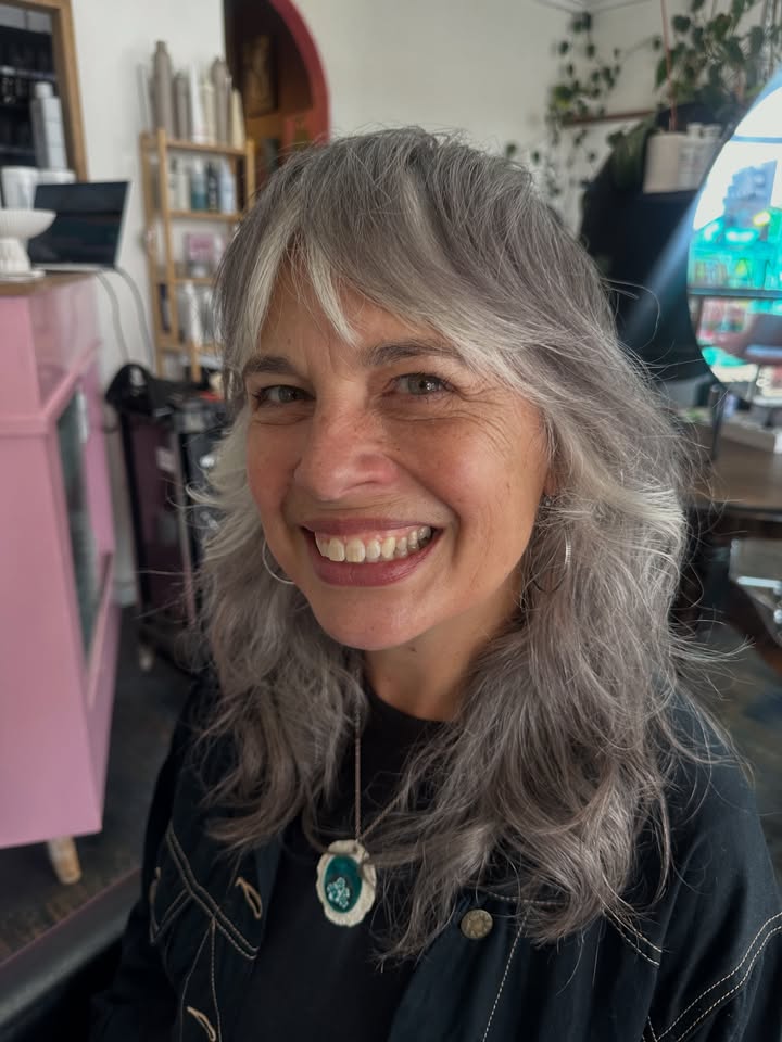 Medium length silver layered hair with light bangs and soft waves.