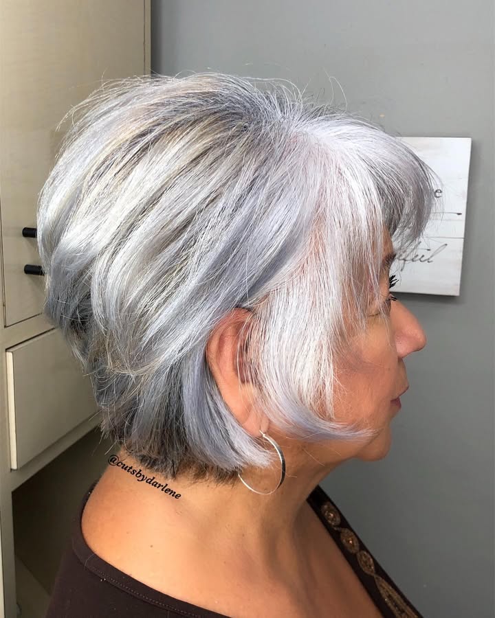 Layered silver bob with side swept bangs and soft natural movement.