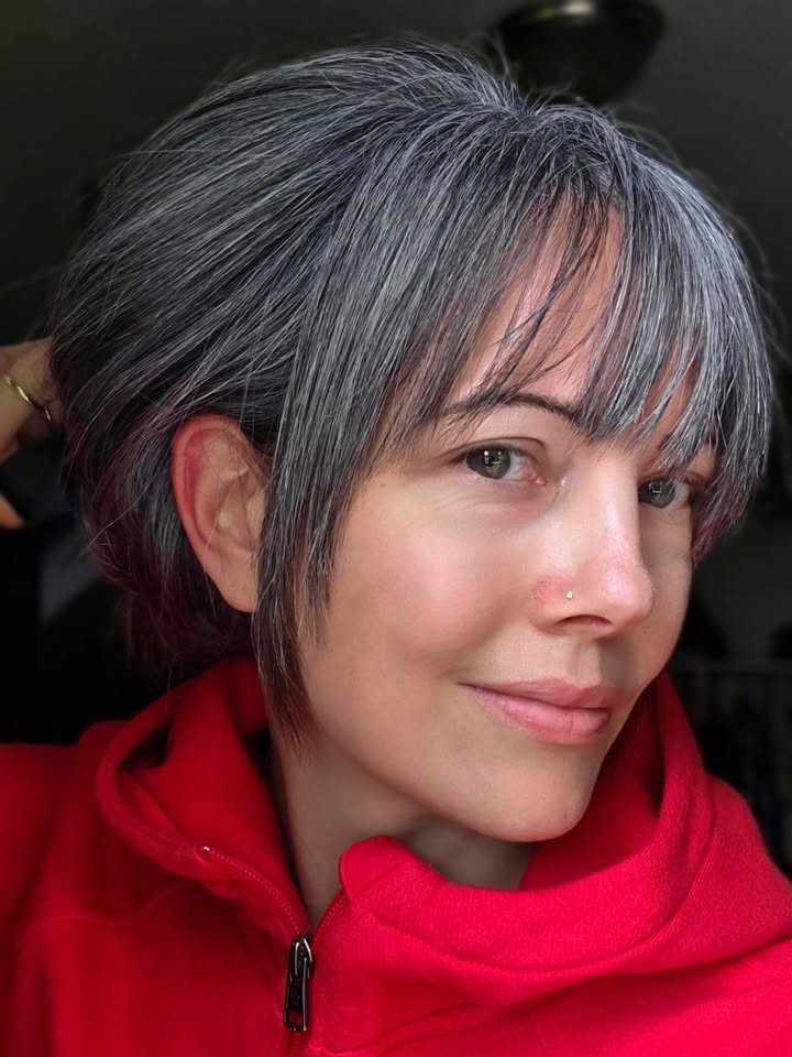 Gray hair styled in a loose updo with wispy bangs and soft face framing pieces.