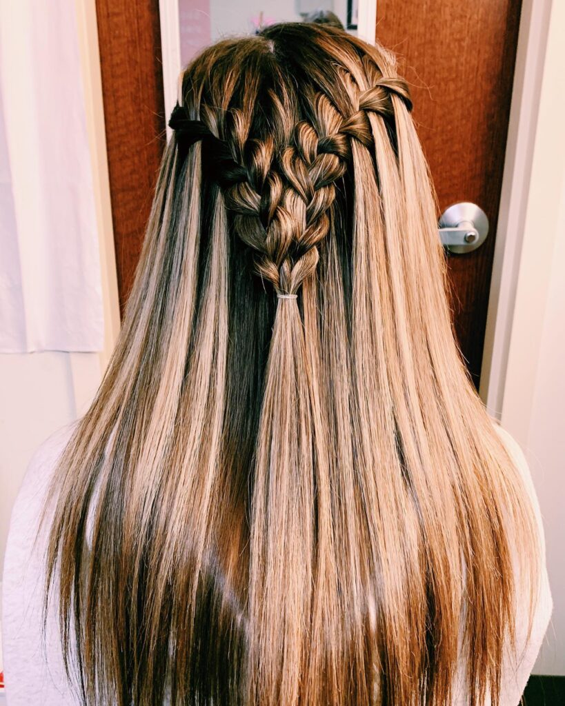 A back view of long, straight, honey blonde hair featuring two waterfall braids that join in the middle to create a heart-shaped design.