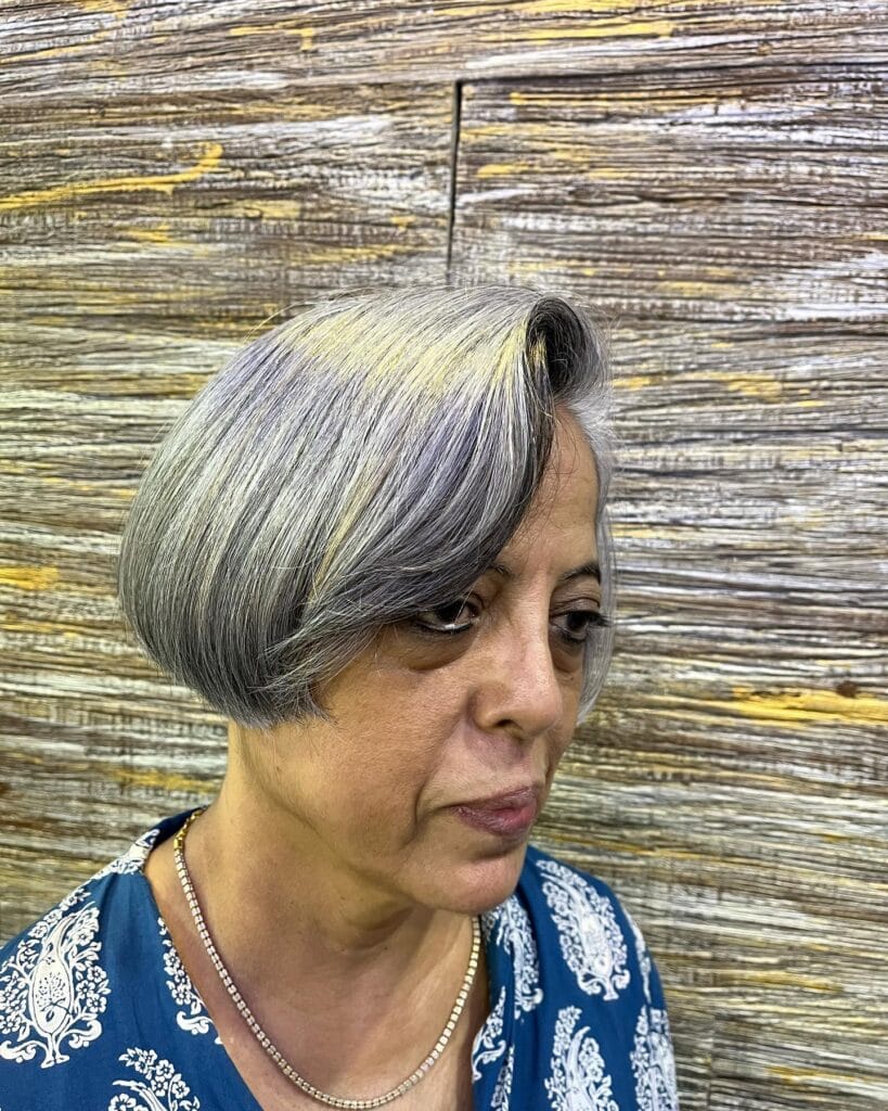 A woman with a sleek, jaw-length, rounded bob hairstyle in a multidimensional steel gray color.