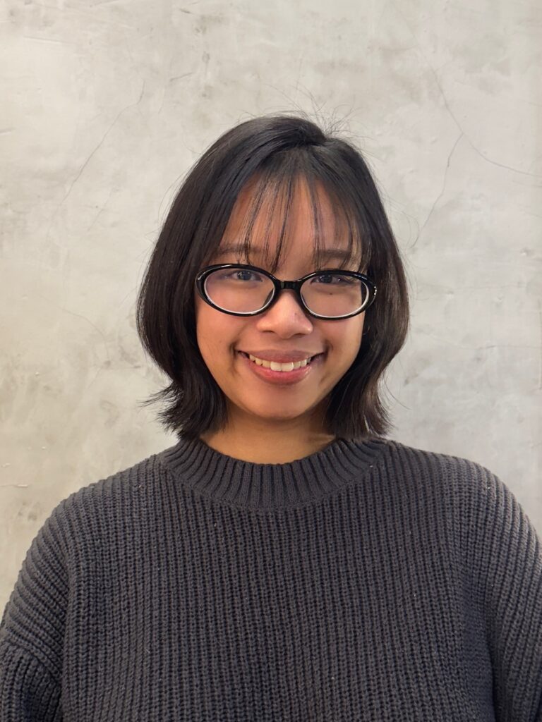 A young woman with a chin-length dark brown bob featuring light wispy bangs and subtly flared-out ends.