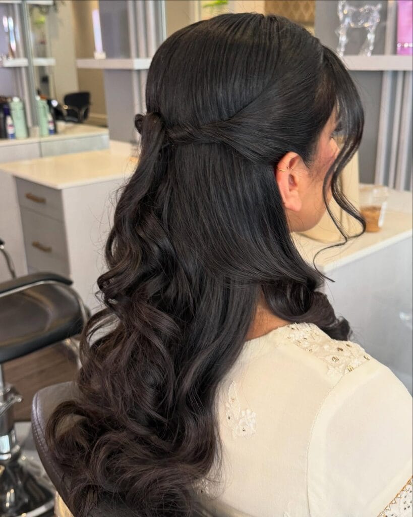 Long dark wavy hair styled half up with soft volume and loose curls.