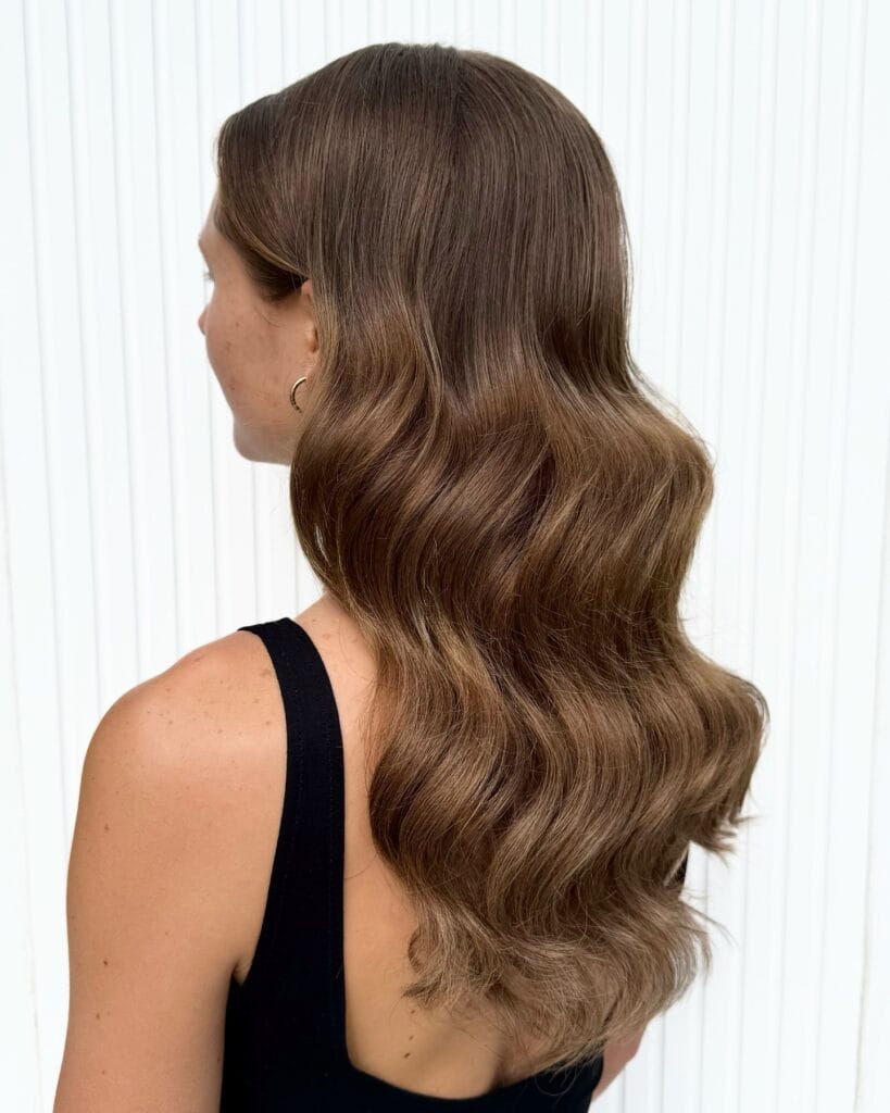 Long brown hair with soft classic waves and blended layers.
