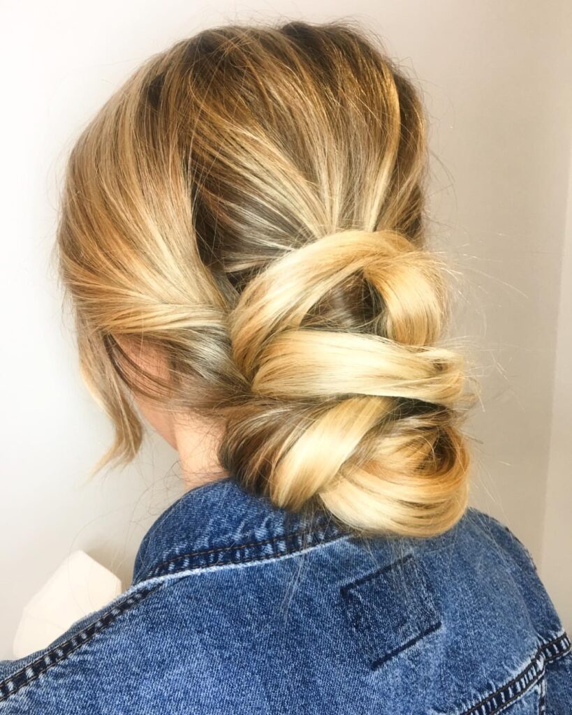 Sleek blonde low rolled bun with a smooth polished finish.