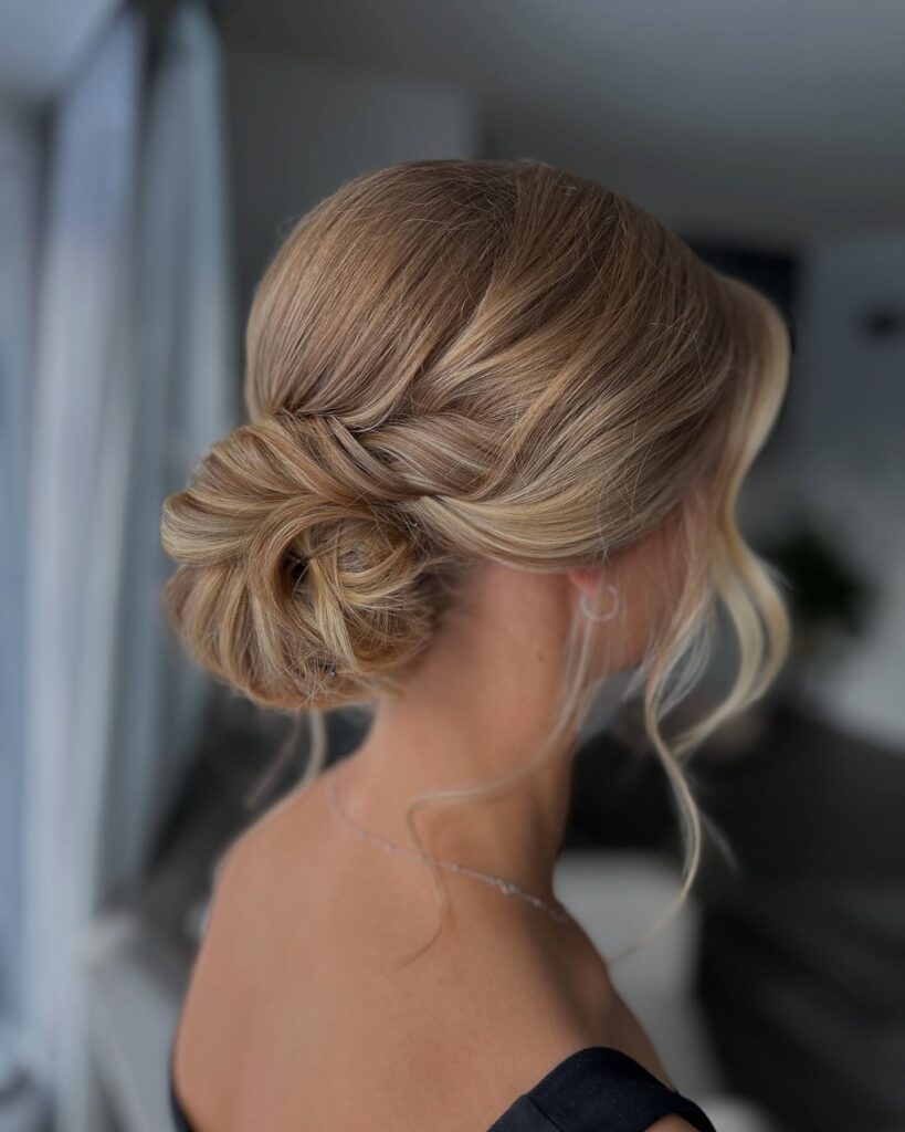 Sleek dark hair styled into a minimal low knot with a smooth finish.