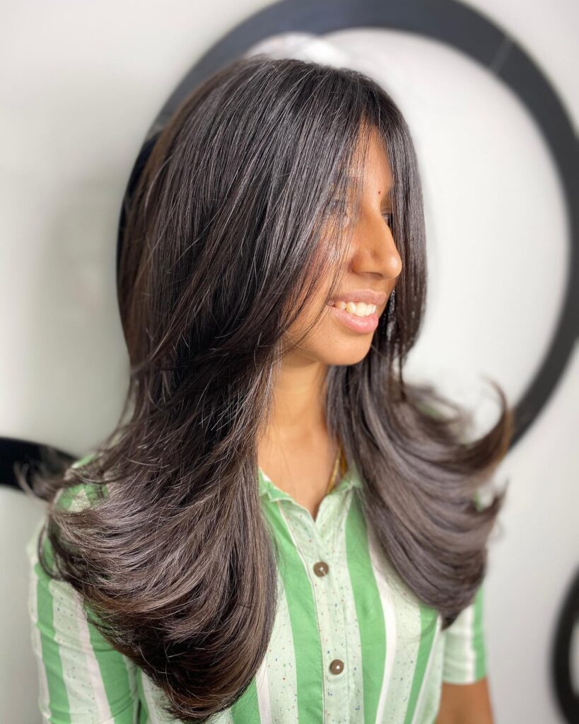 Long layered hair with smooth blowout and softly curved ends.