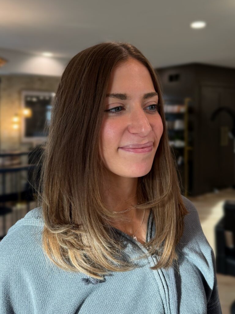 Shoulder length layered brunette hair with soft highlights and smooth inward styled ends.