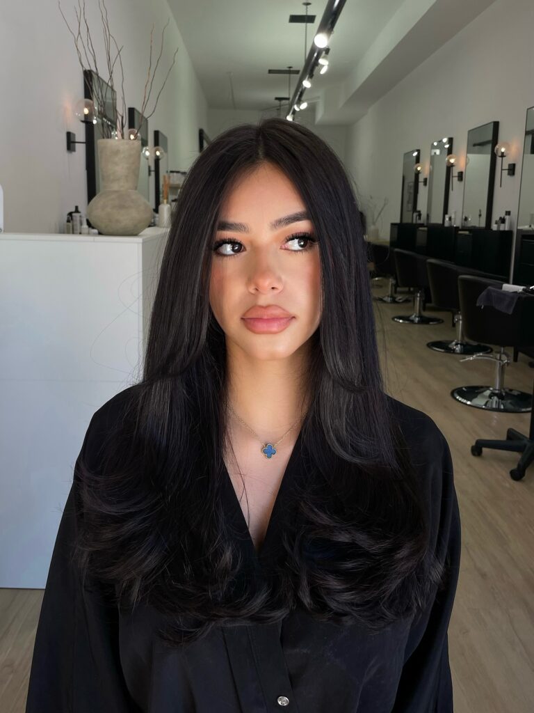 Long straight dark hair with subtle tapered layers and a sleek finish.