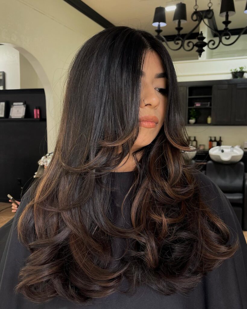 Long layered wavy hair with soft volume and smooth top section.
