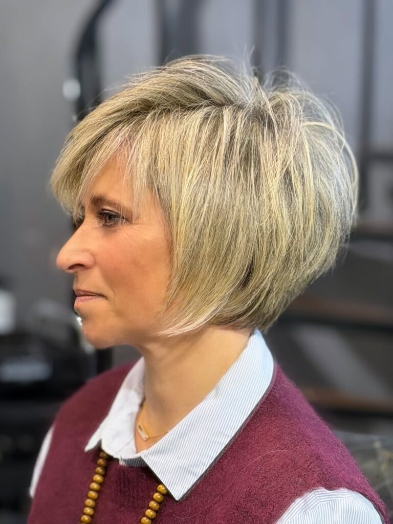 A woman with a voluminous layered pixie bob and soft side bangs.