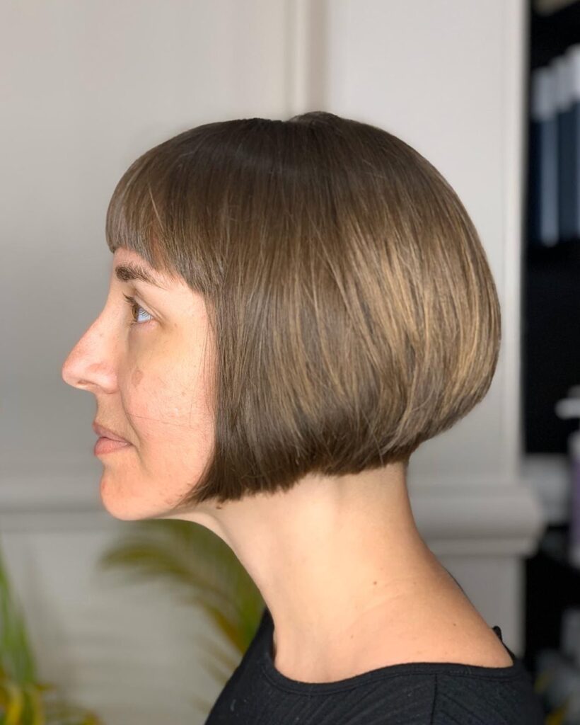 A woman with a sharp chin length bob and blunt bangs.