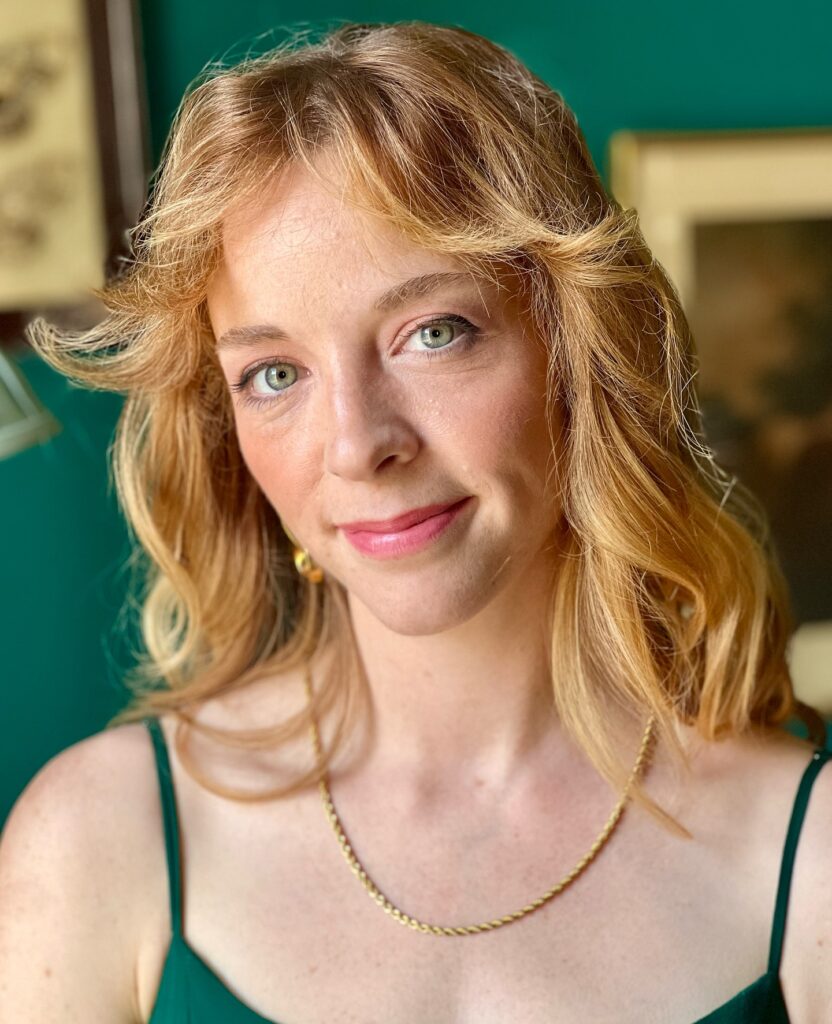 A woman with strawberry blonde shoulder length hair featuring outward flicked curtain bangs and soft waves.