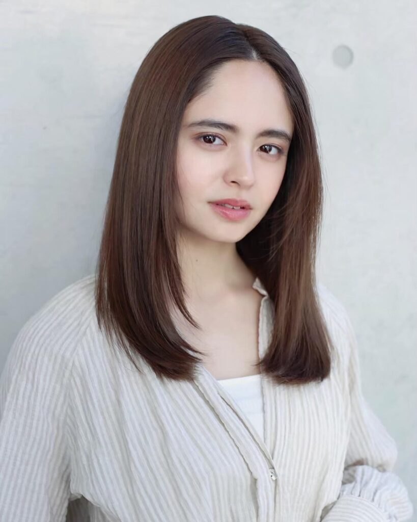 A woman with sleek shoulder length mocha brown hair styled straight with a center part and soft face framing pieces.