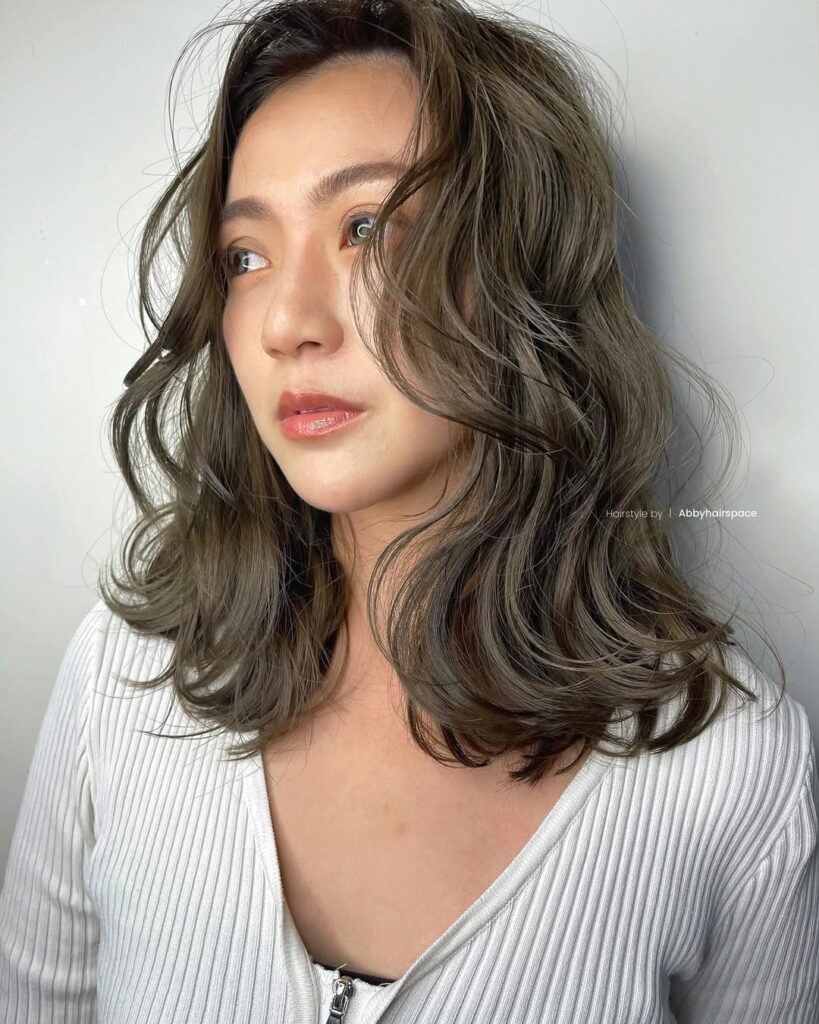 Shoulder length wavy lob with soft layers and cool ash brown tones styled in loose texture.
