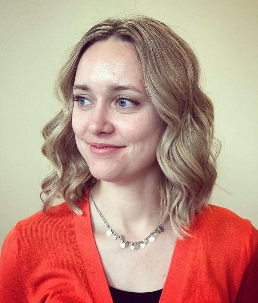 Light blonde shoulder length hair styled in soft loose waves with natural volume and a clean finish.