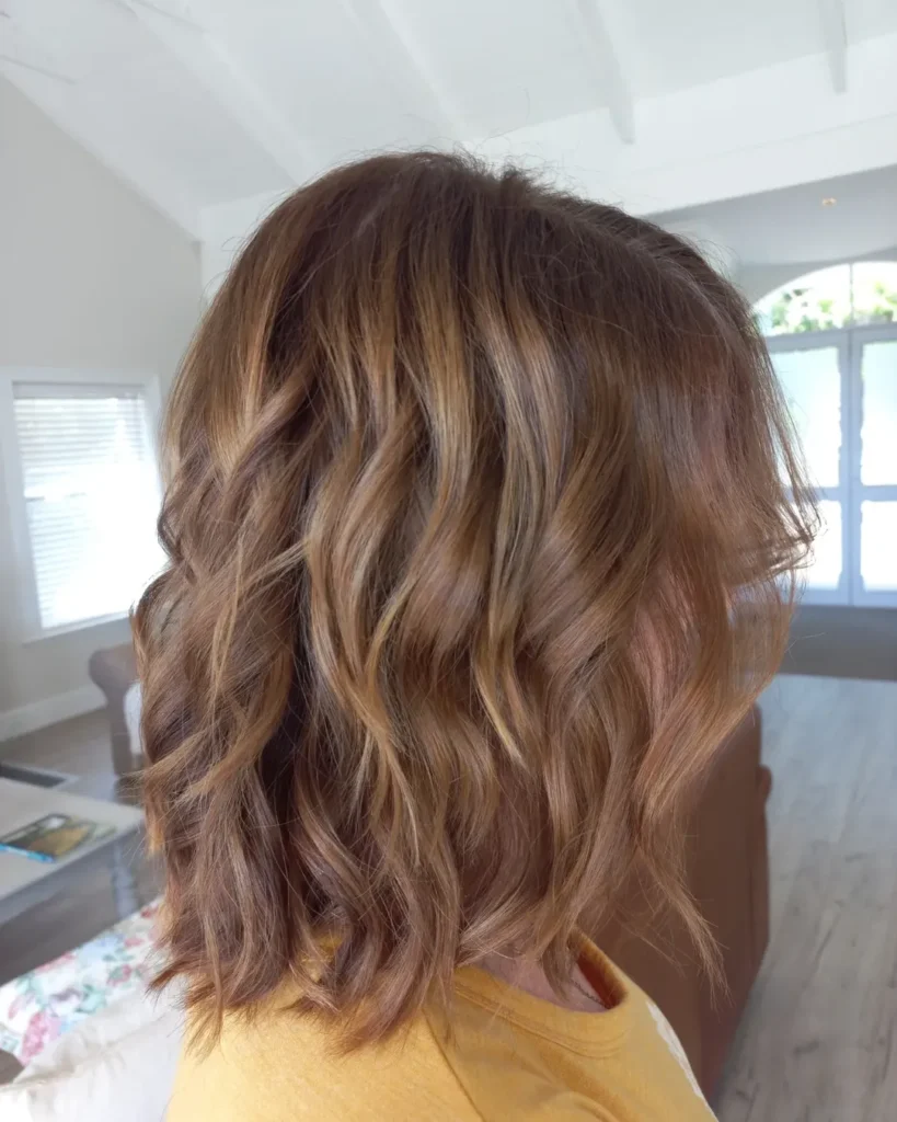 Medium length brown hair with soft layers and natural waves creating movement and texture.