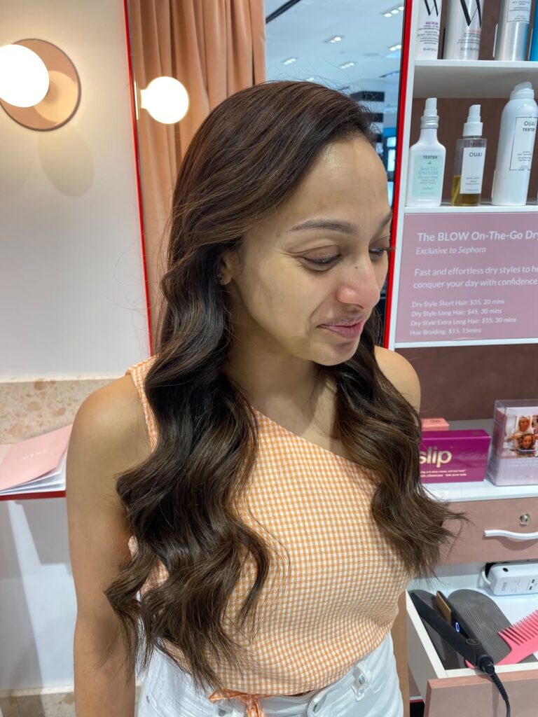 Long dark brunette hair styled in soft waves with a subtle side part and smooth top.