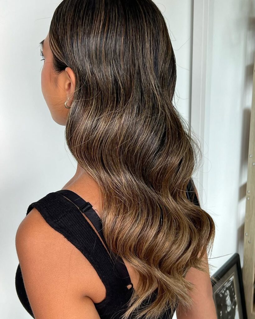 Long wavy hair with blended balayage highlights and soft natural waves adding dimension.