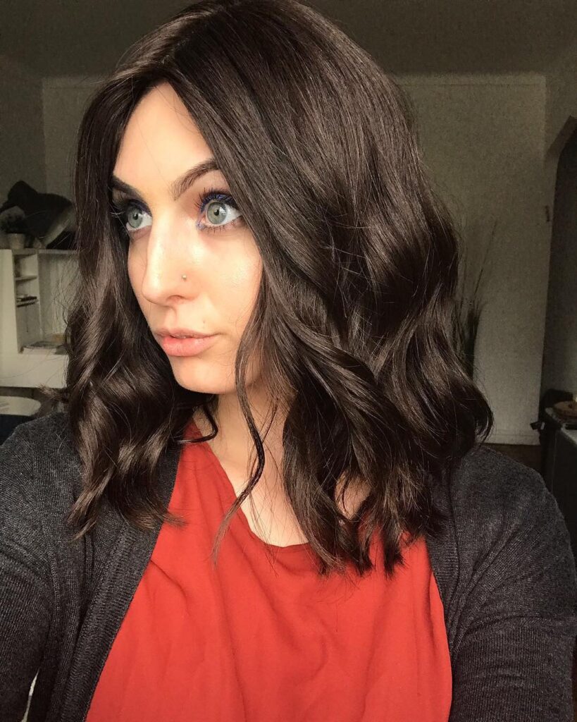 Shoulder length brunette hair styled in soft defined waves with a side part for a polished work look.