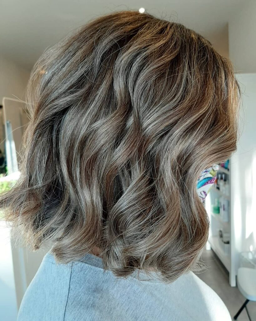 Short wavy bob with soft layers and dimensional highlights creating volume and texture.