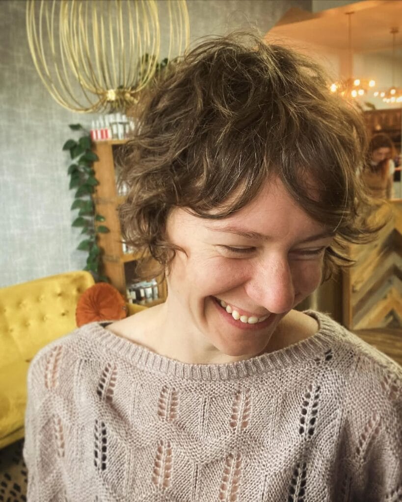 A woman with a short shag haircut featuring soft waves and a wispy fringe.