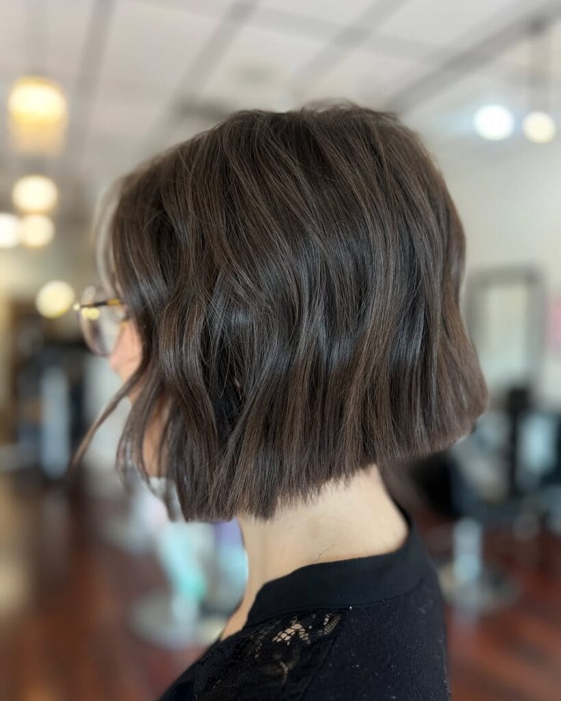 A woman with a short dark brown wavy bob with softly blunt ends and a smooth finish.