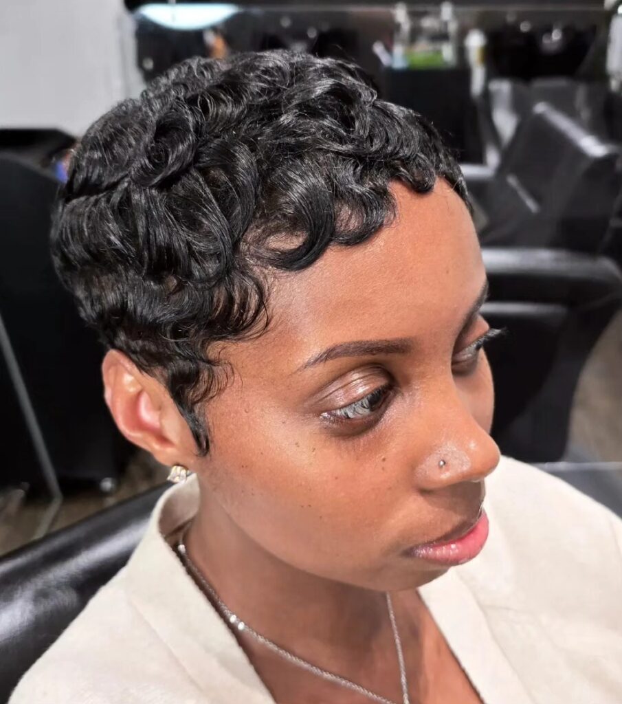 A woman with a short black pixie cut styled into glossy and precise finger waves.