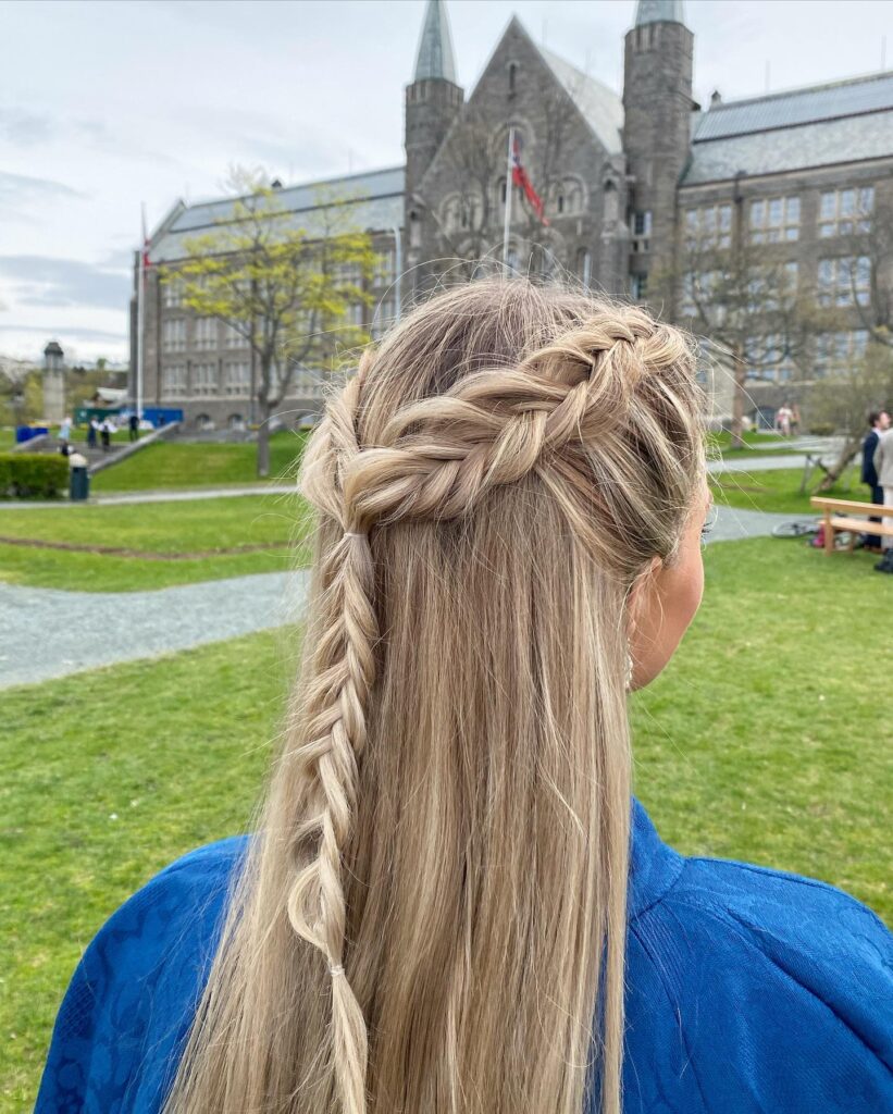 A rear view of a woman with long, straight ash blonde hair featuring a half-up braided crown style.