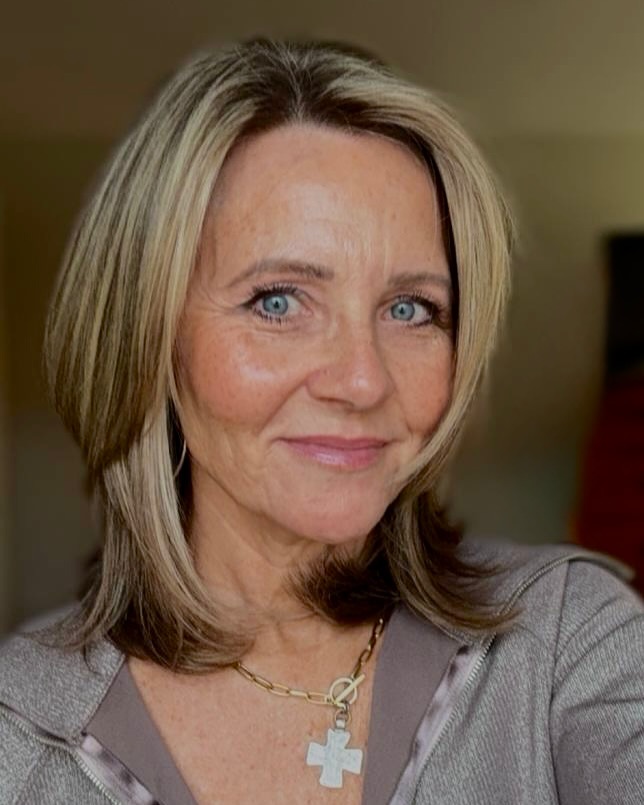 A woman with shoulder-length sandy blonde hair featuring wispy layers and sun-kissed highlights styled in a soft, textured shag.