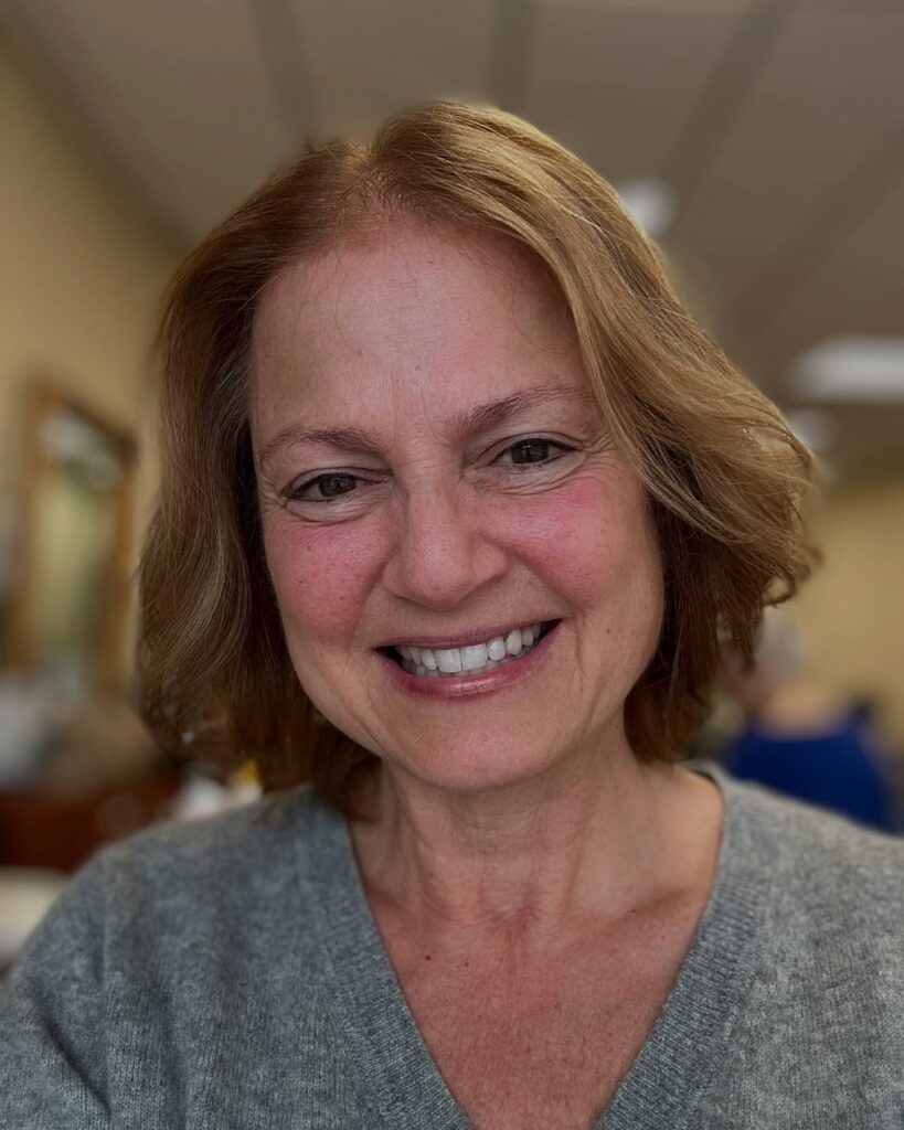 A woman with a shoulder-length golden honey-blonde hairstyle featuring soft layers and a subtle wavy texture.