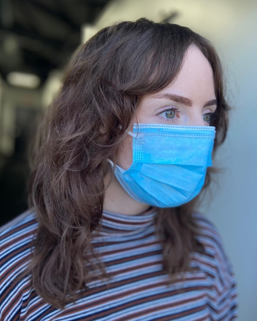 A woman with a medium-length chestnut brown shag haircut featuring soft curtain bangs and tousled layers.