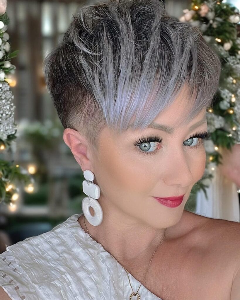 A woman with a short pixie cut featuring buzzed sides and textured lavender and silver layers on top.