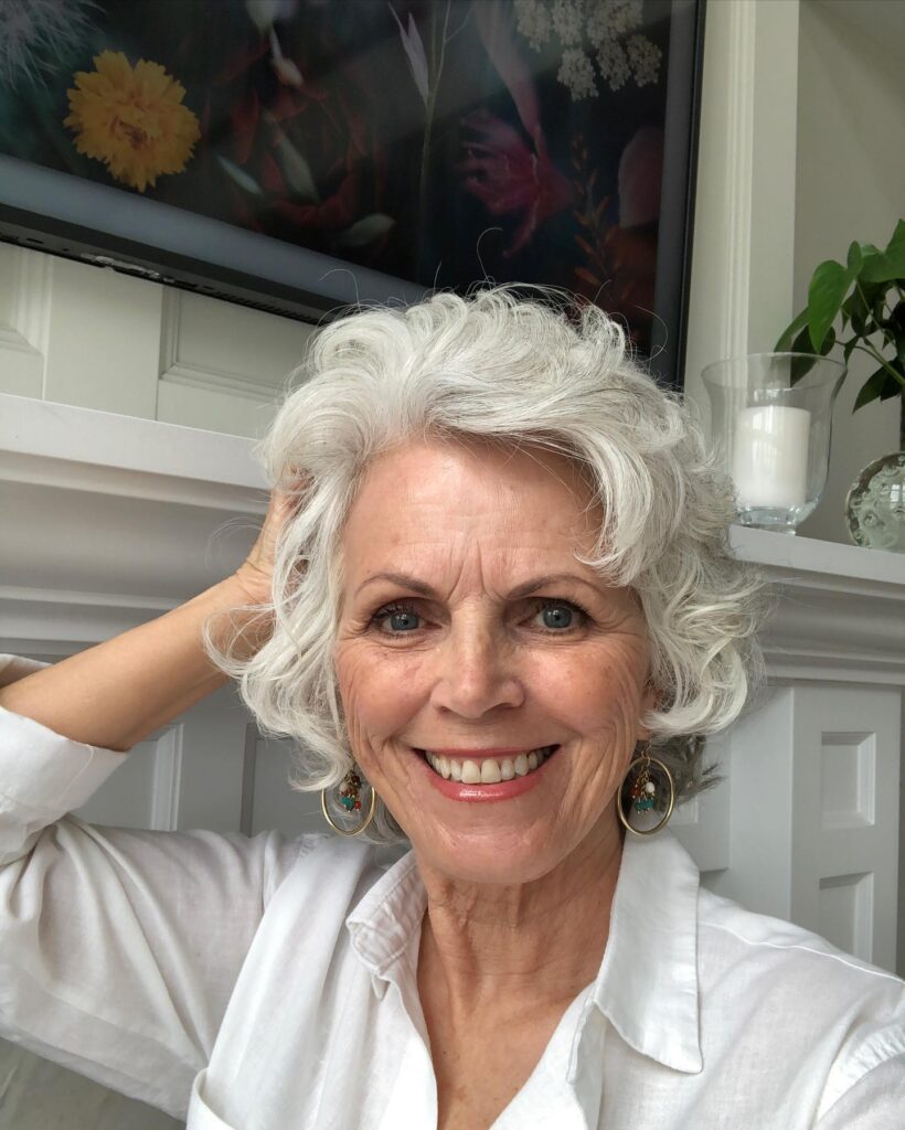 A woman with a chin-length pearl-white bob featuring soft voluminous waves and feathered layers.