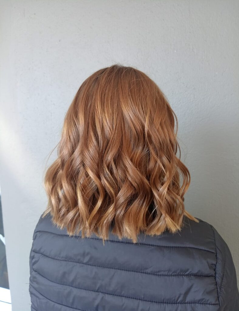 Medium length brown hair styled in soft loose curls viewed from the back.