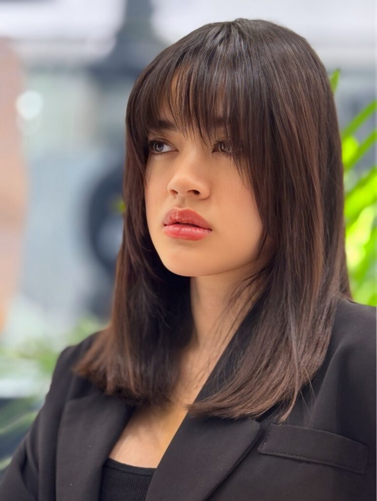 Medium length straight dark brown hair with a soft wispy fringe.