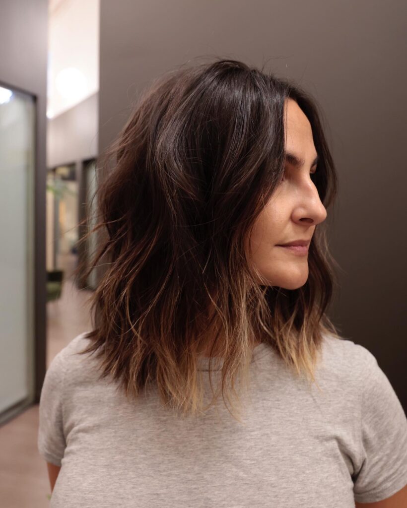 Wavy textured lob with dark roots and lighter ends styled in soft loose waves.