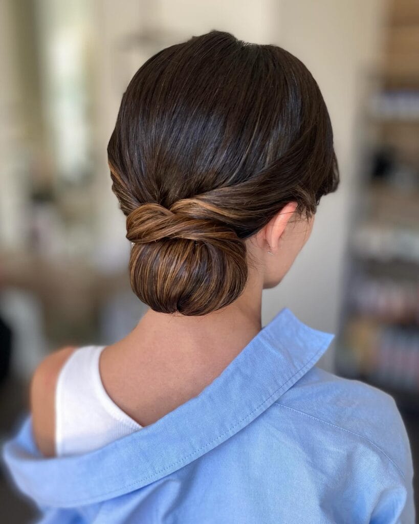 Brown hair styled into a softly wrapped low bun with slight volume at the crown.