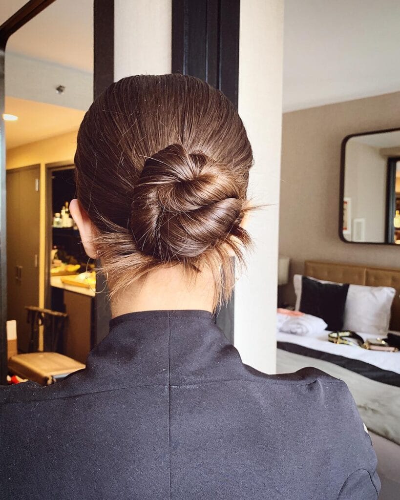 Brown hair styled into a detailed braided bun with visible woven texture at the back.