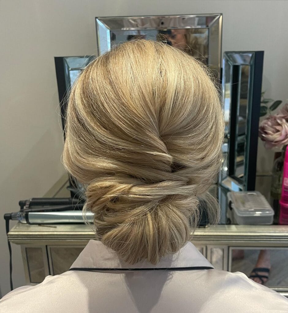 Light blonde hair styled into a classic French twist that transitions into a low bun.