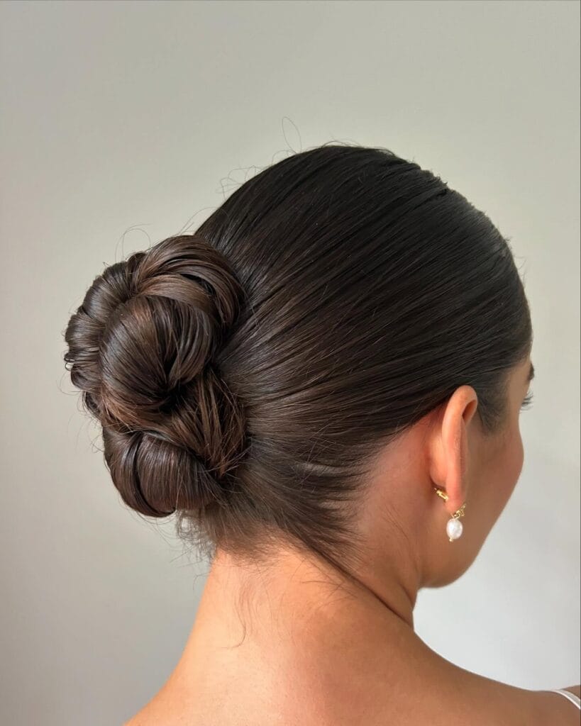 Dark hair styled into a sleek and tightly secured low bun with a smooth finish.
