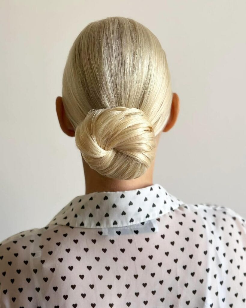 Blonde hair styled into a clean twisted low bun at the nape.