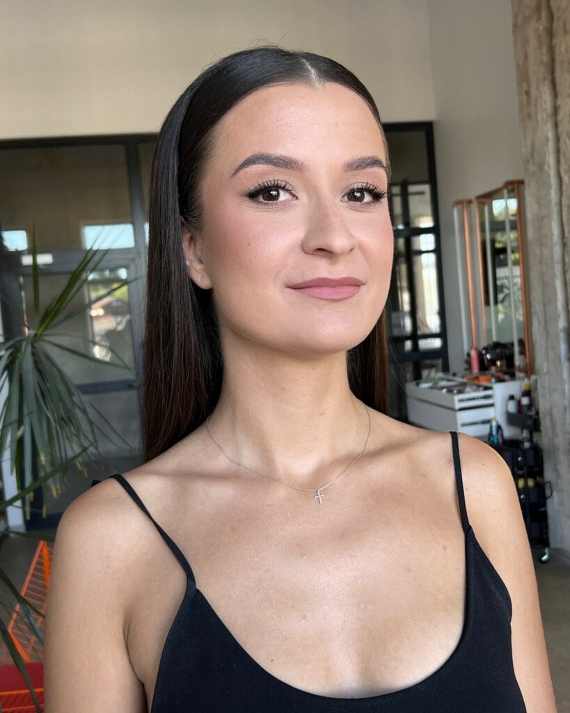 Long dark straight hair styled with a center part and tucked behind the ears.